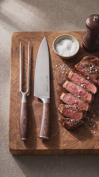 Set Parrillero Toledo Simplit — cuchillo 21 cm y tenedor trinchando carne asada